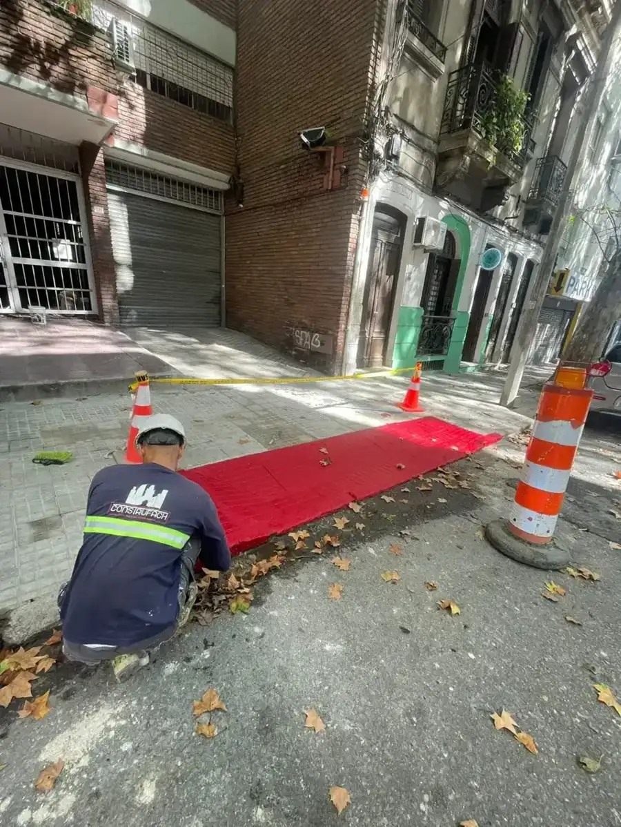Operario de ConstruFach pintando la rampa de accesibilidad roja en la vereda