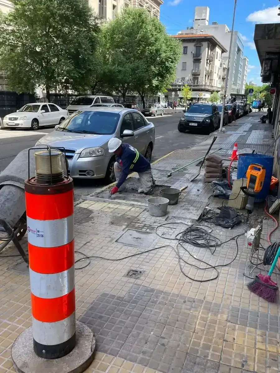 Operario colocando baldosas con la vereda señalizada en plena vía pública